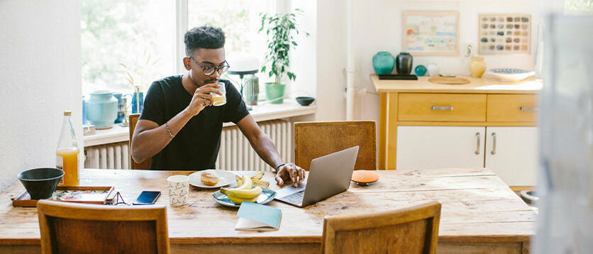 Mann mit Glas in der Hand vor dem Laptop © Maskot / Getty Images